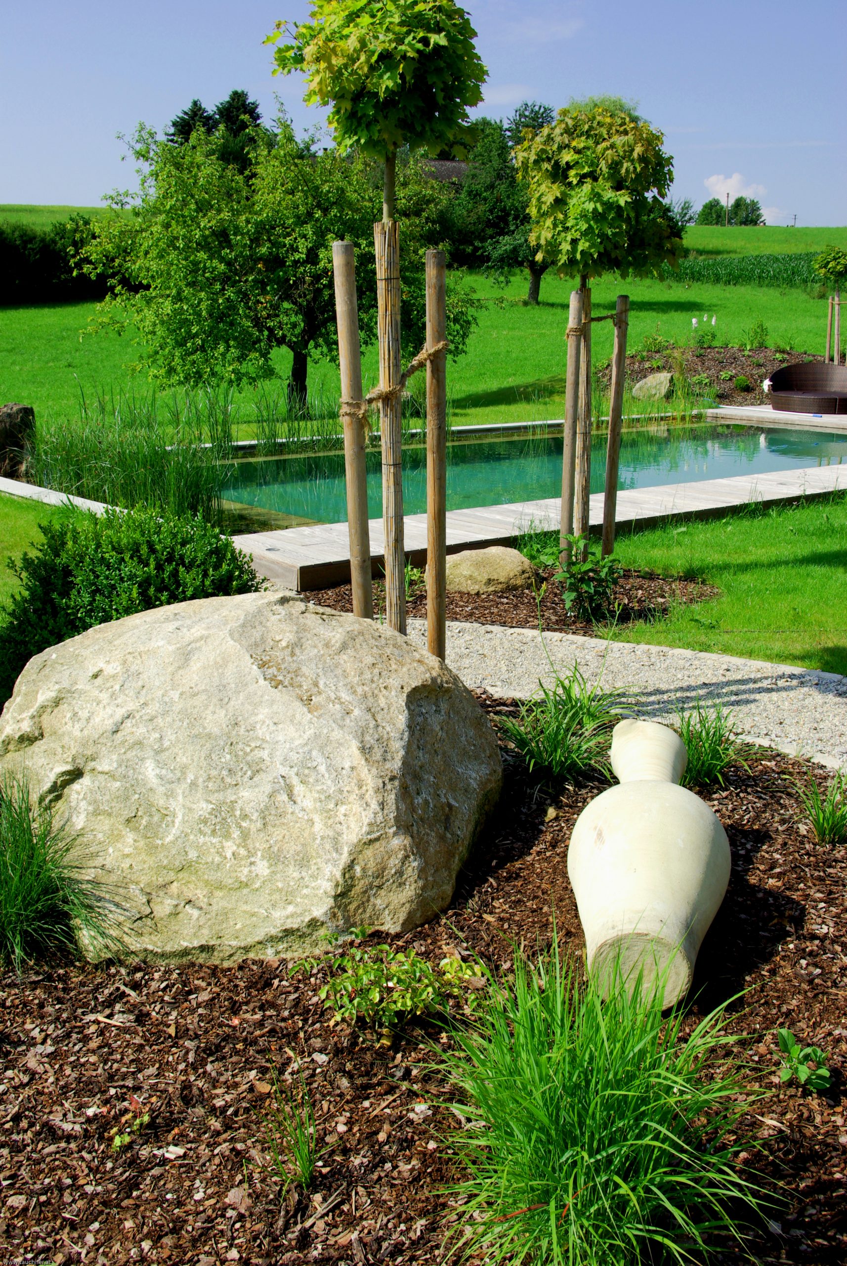 Naturpool mit großem Naturstein in der Gartengestaltung